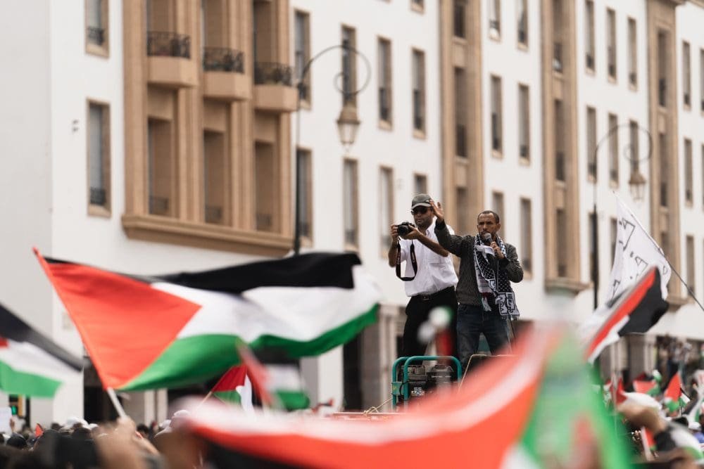 Two men are waving to the crowd from a balcony.